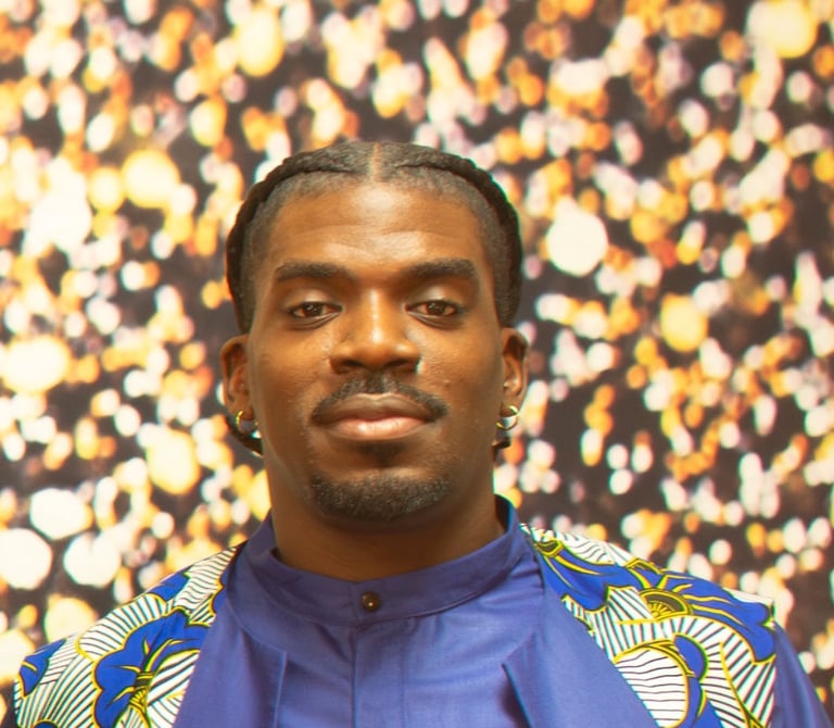Man wearing a blue and yellow patterned shirt against a blurred gold and brown bokeh background