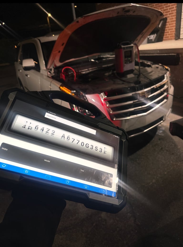 Mechanic holding diagnostic scanner displaying VIN while working on red and white truck with open hood at night
